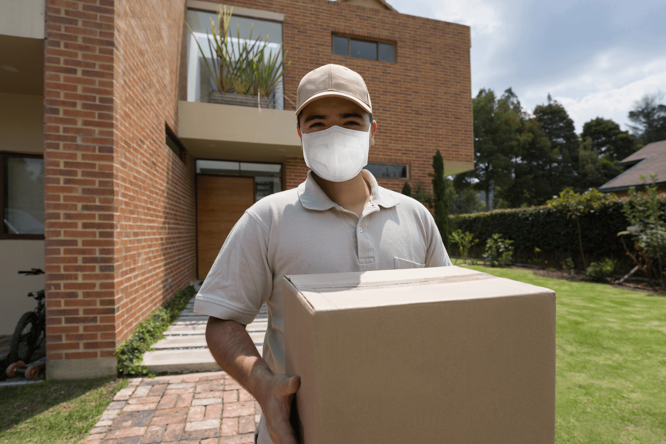 Delivery person holding package outside a house.