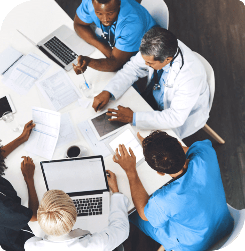 Doctors collaborating around a table with laptops.